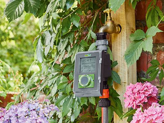 Bewässerungstimer und Wasserhahn im Garten.
