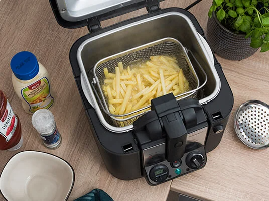 Pommes frites werden in einer Friteuse gebraten.