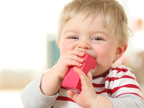 Baby spielt mit roten Bauklötzen.