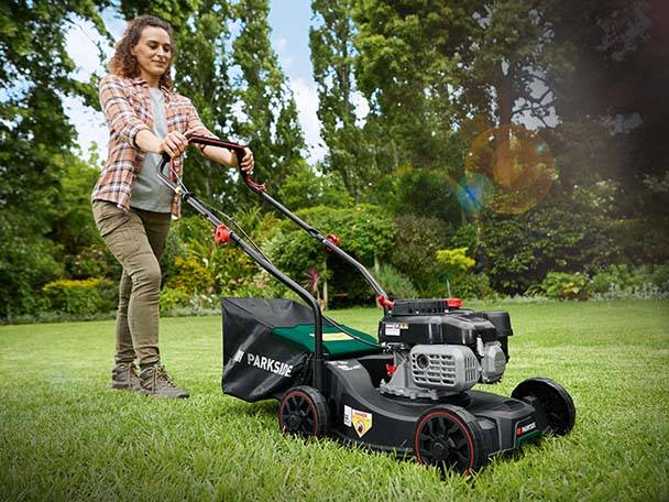 Frau benutzt einen Parkside Rasenmäher.