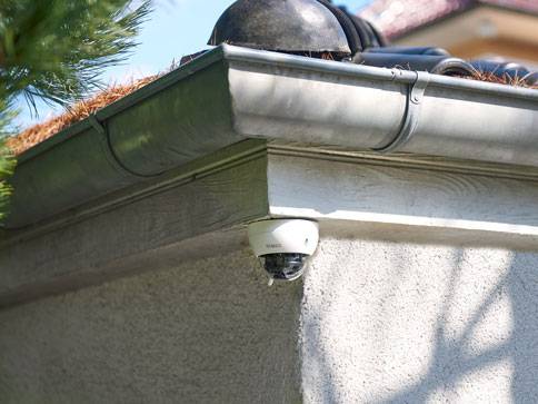 Überwachungskamera und Dachrinne an der Hauswand.