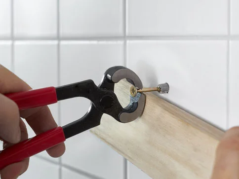 Zange, Schraube und Holzstück zum Befestigen an der Wand.