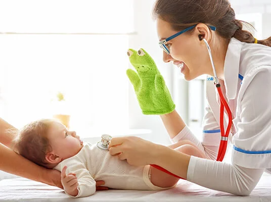 Ärztin untersucht Baby mit Stethoskop und Handpuppe.