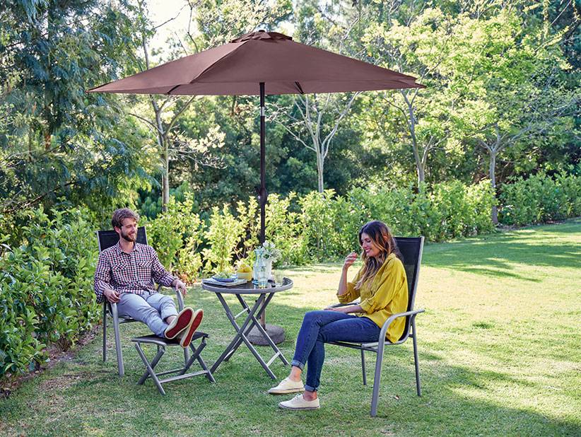 Gartenmöbel: Sonnenschirm, Stühle und Tisch auf dem Rasen.