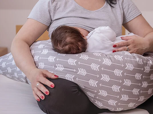 Stillen, Baby und Kissen mit Pfeilmuster