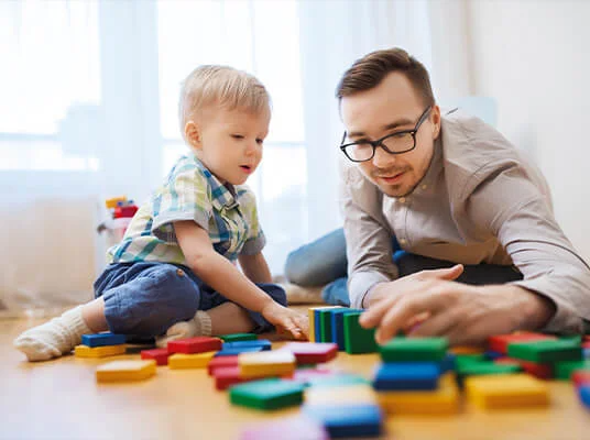 Vater und Sohn spielen mit bunten Holzwürfeln.