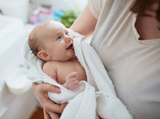 Lächelndes Baby in weißem Handtuch.