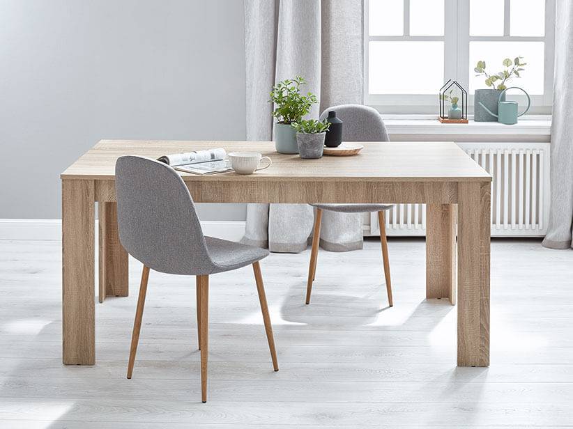 Heller Holztisch und graue Stühle.