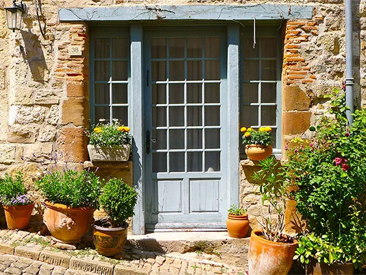 Ländliche Tür mit Blumen und Pflanzen geschmückt.