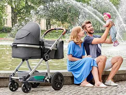 Familie mit Kinderwagen am Brunnen.