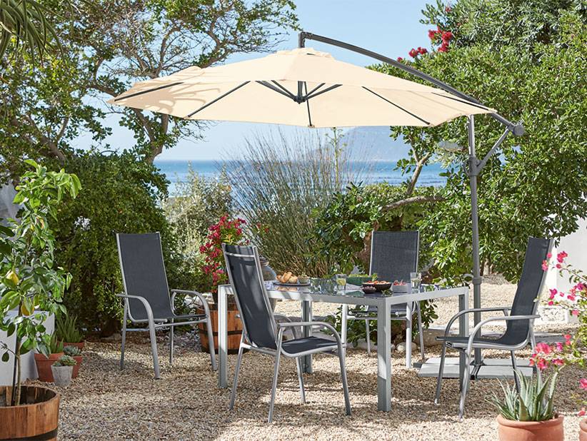 Beigefarbener Sonnenschirm und graue Gartenmöbel.