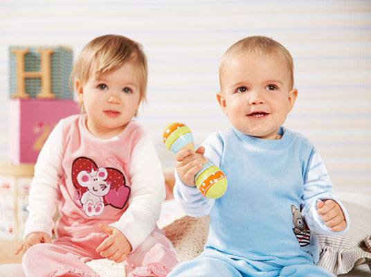 Kleinkinder spielen mit Maracas; niedliche Designs auf Kleidung.