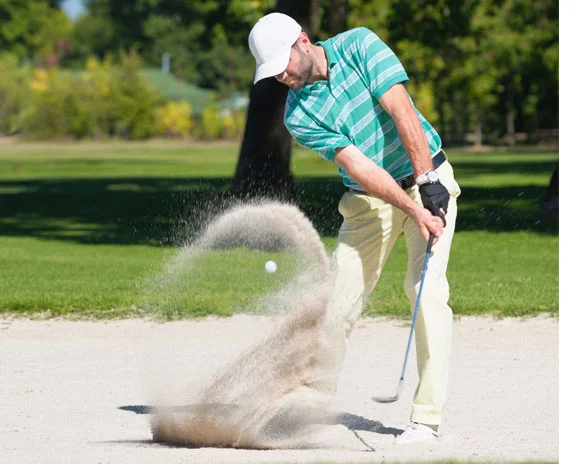 Golfer schlägt Ball aus Bunker.