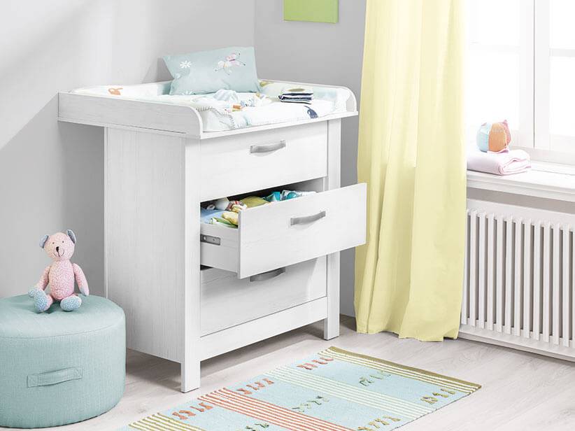 Weißer Wickeltisch mit drei Schubladen.