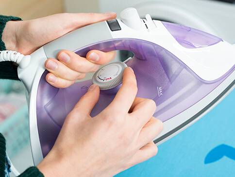 Lilafarbenes Bügeleisen im Gebrauch.