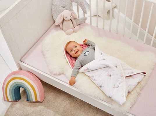 Baby in Decke gewickelt, Decke mit Hasenmotiv und Kissen.