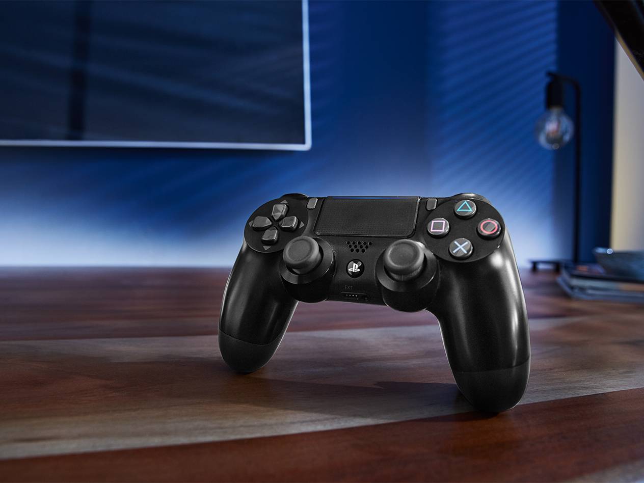 PlayStation-Controller auf einem Holztisch neben dem Fernseher.