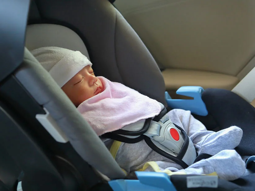 Neugeborenes schläft im Autositz.