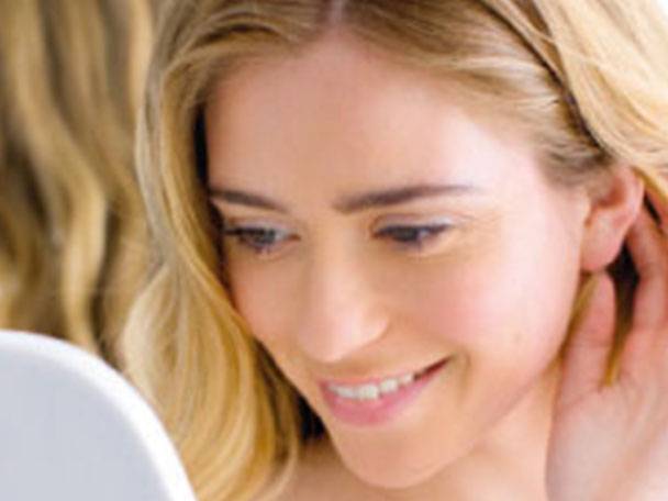 Frau betrachtet sich im Spiegel.