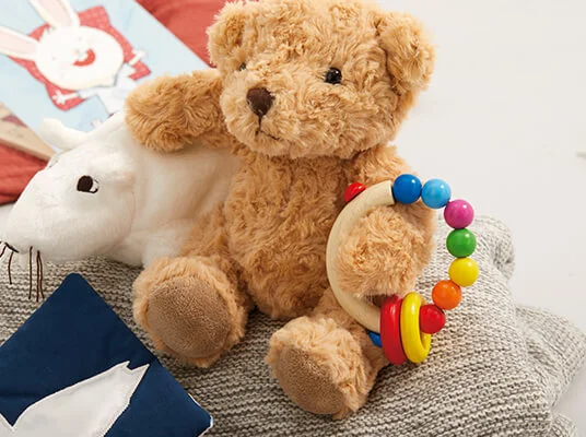 Plüschtiere und Babyspielzeug: Bär, Maus und bunte Rassel.
