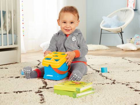 Baby spielt mit Plastikspielzeug und Büchern.