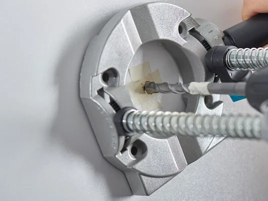 Bohrmaschine und Bohrer in einer Wandhalterung.