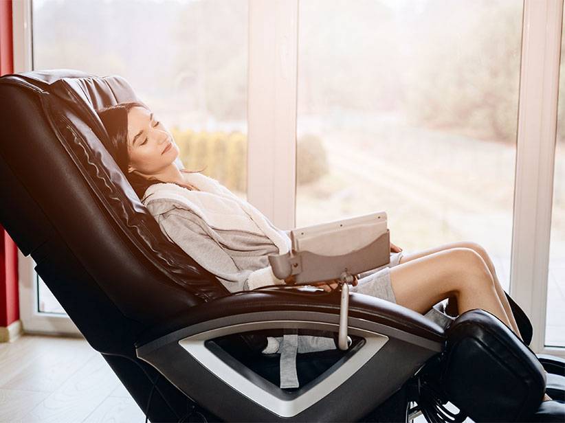 Frau entspannt sich in einem Massagesessel.