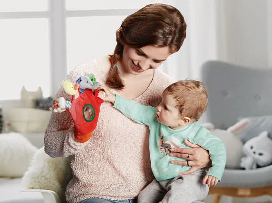 Mutter und Kind spielen mit einer Handpuppe.