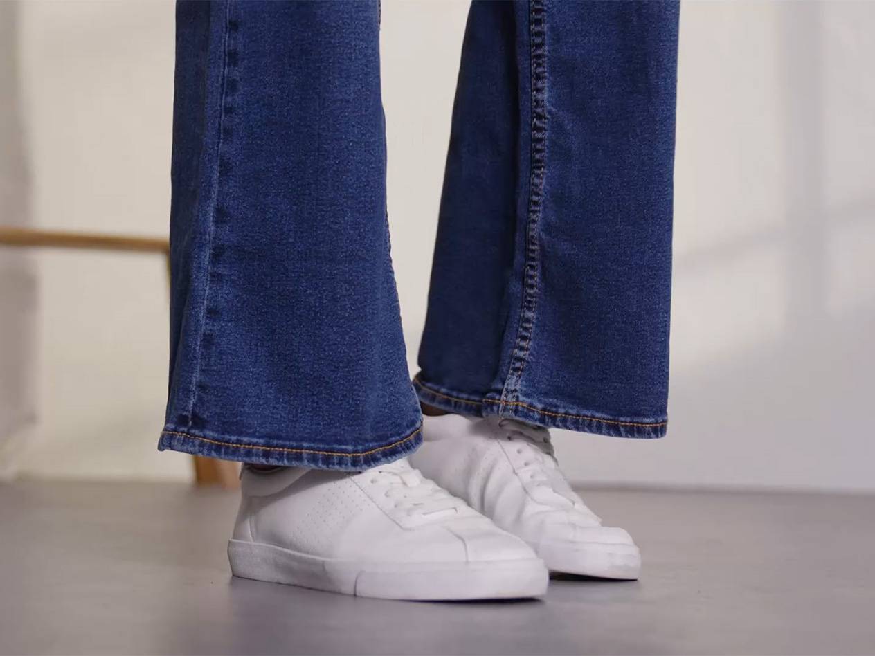 Bootcut-Jeans und weiße Sneaker.
