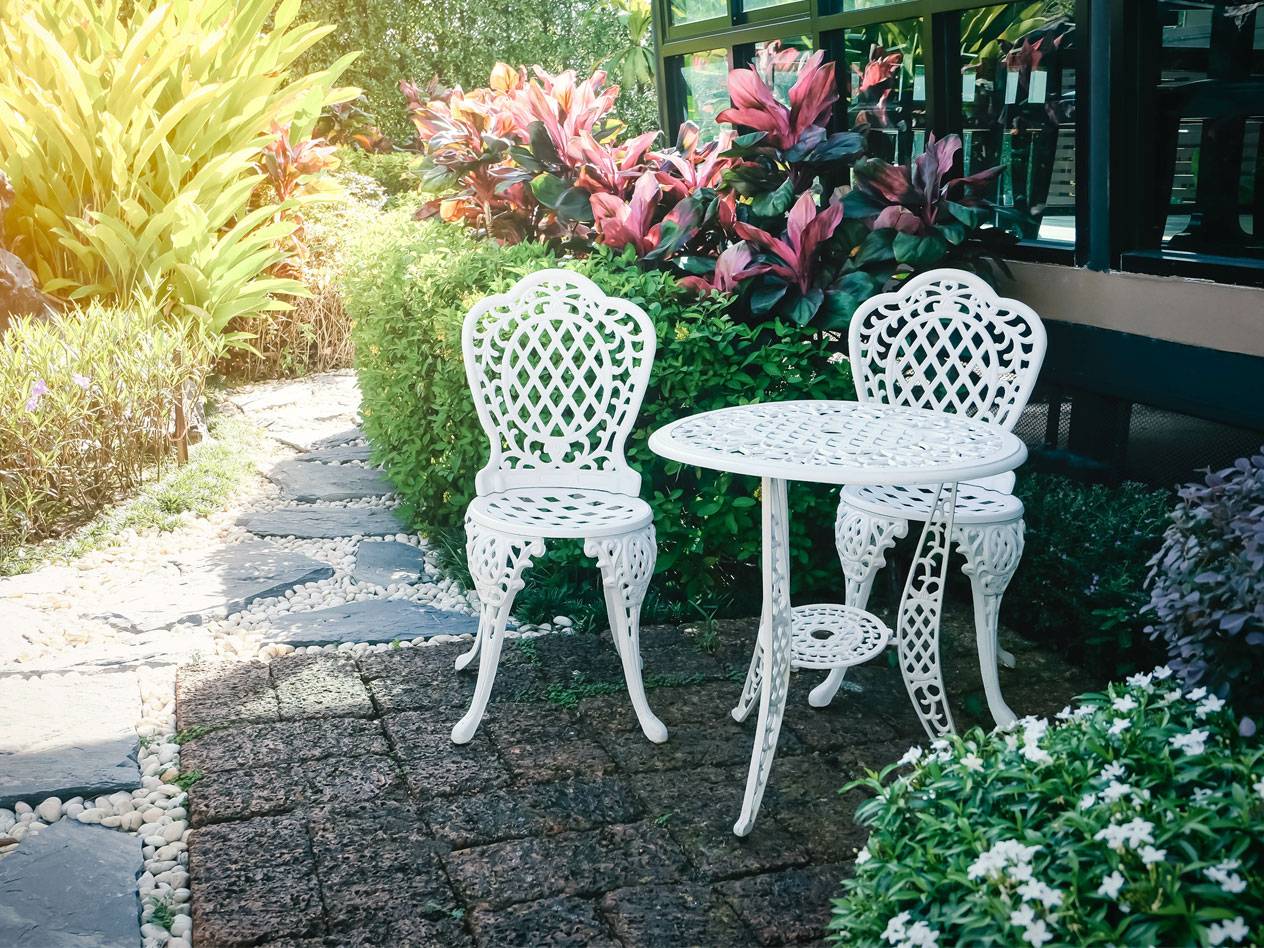 Weißer Metall-Gartentisch mit zwei Stühlen.