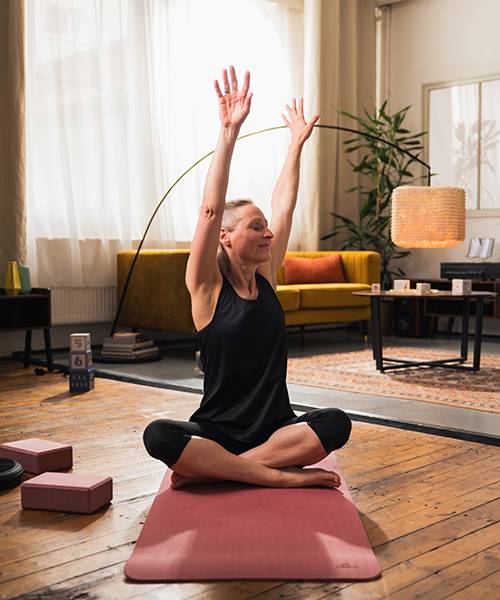 Frau macht Yoga mit Blöcken und Matte.