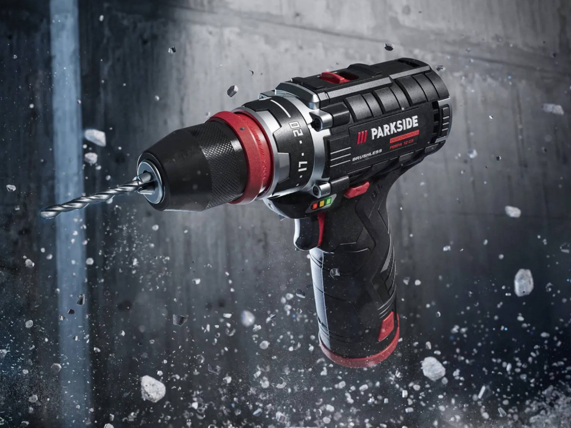 Schwarz-rote Parkside Bohrmaschine, umgeben von fliegenden Trümmern.