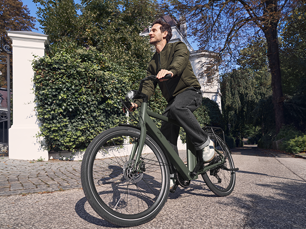 Mann fährt VanMoof E-Bike in Wohngegend.