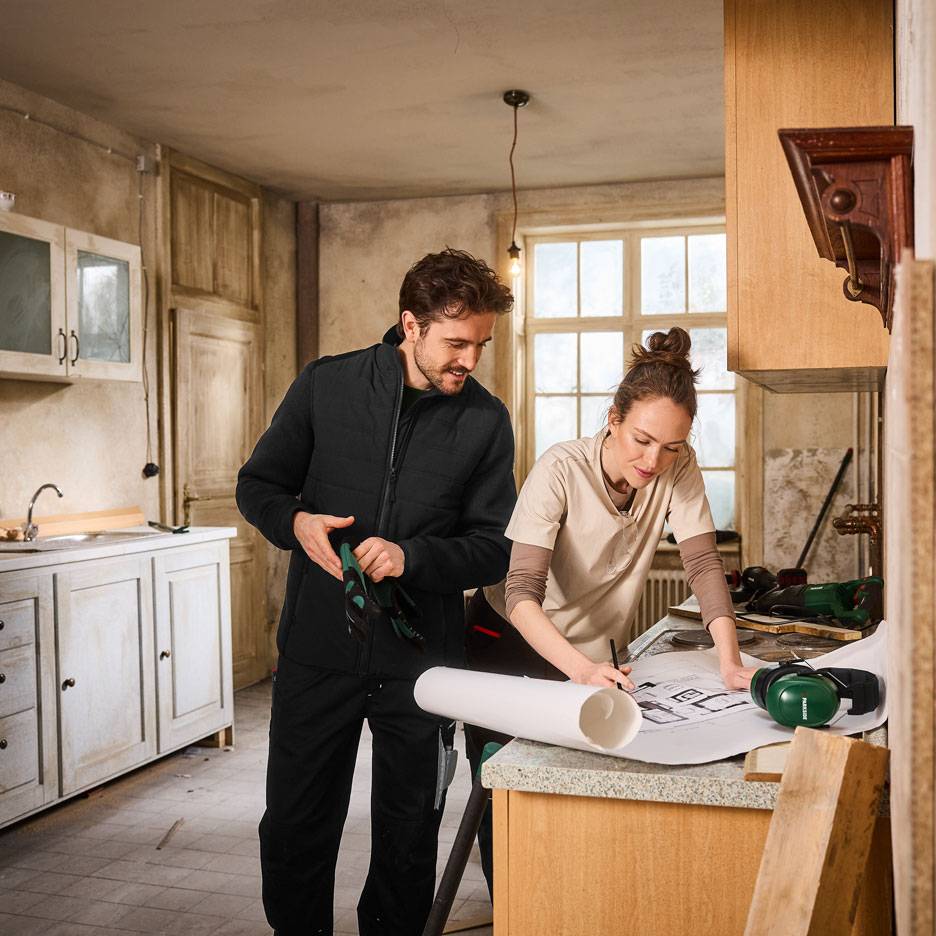 Mann und Frau in Arbeitskleidung planen eine Küchenrenovierung.