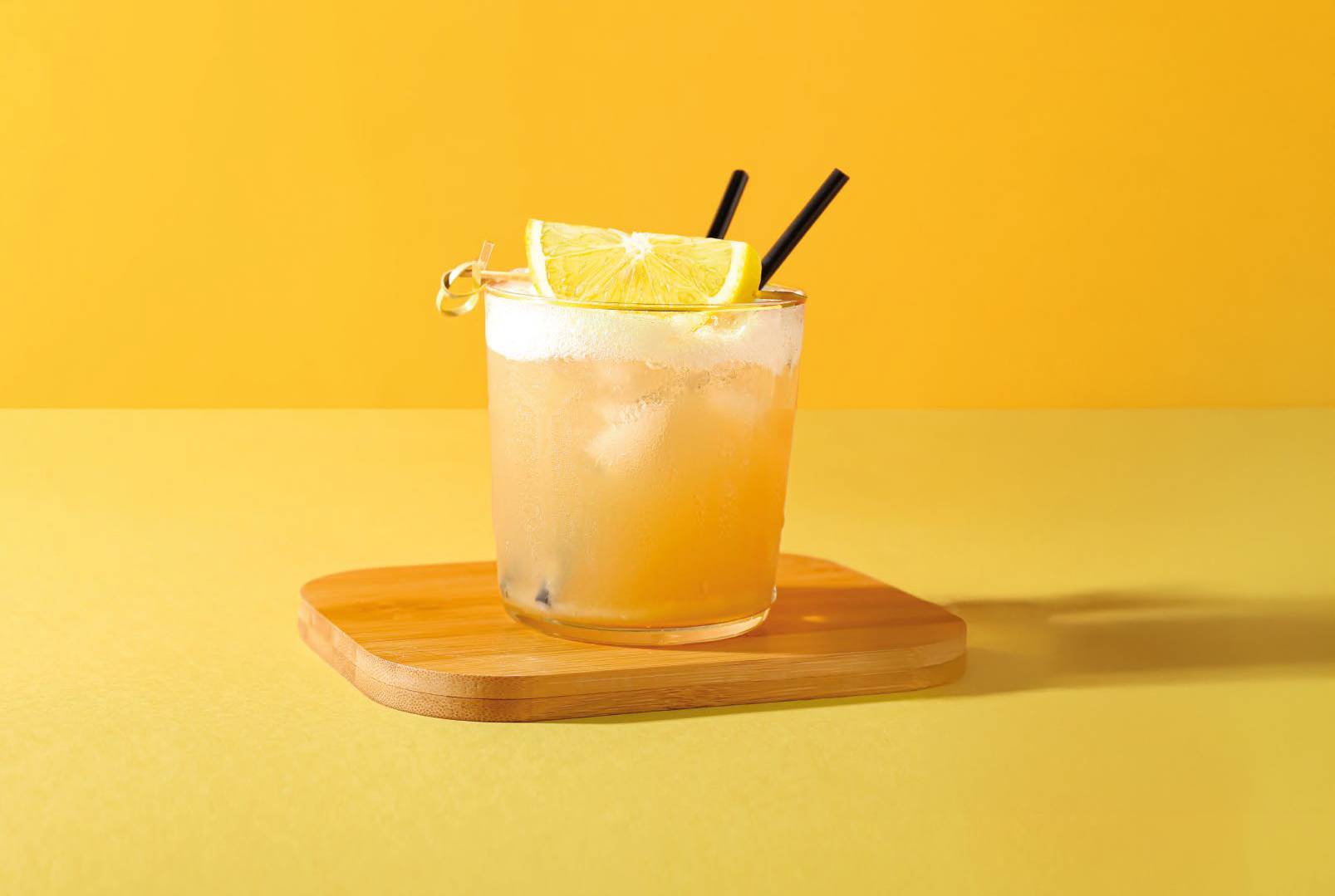 Zitronencocktail auf einem Holzuntersetzer.