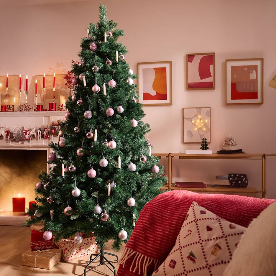 Weihnachtsbaum mit rosa und silbernen Kugeln in einem gemütlichen Wohnzimmer.