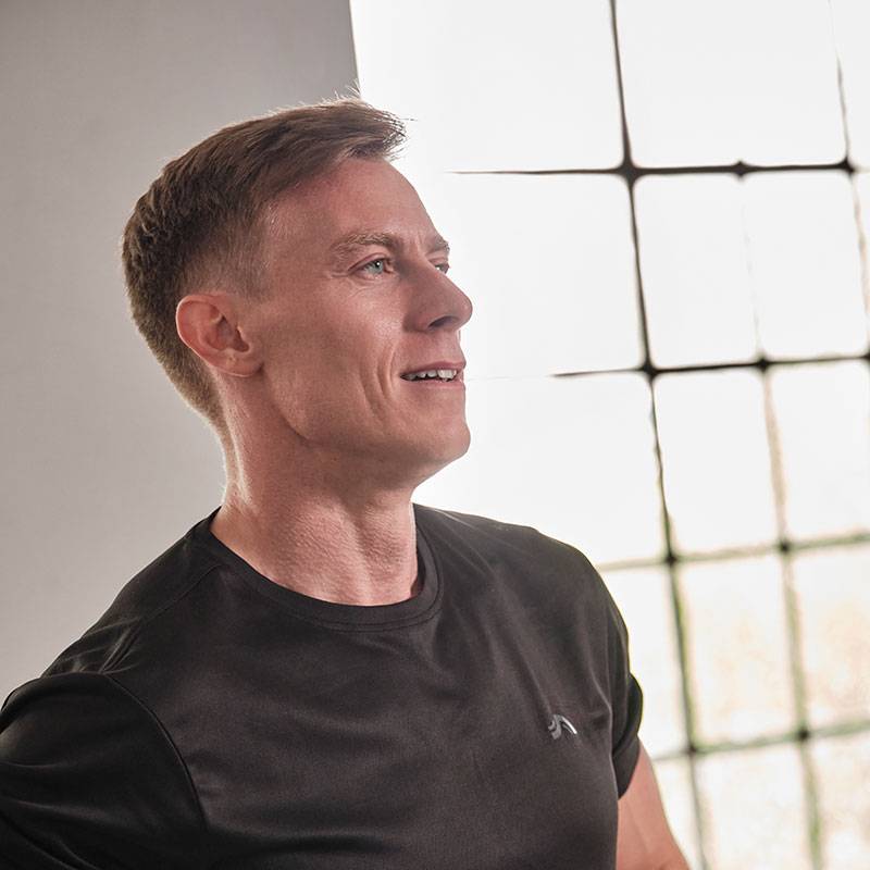 Ein Mann in einem schwarzen T-Shirt schaut zu einem Fenster.