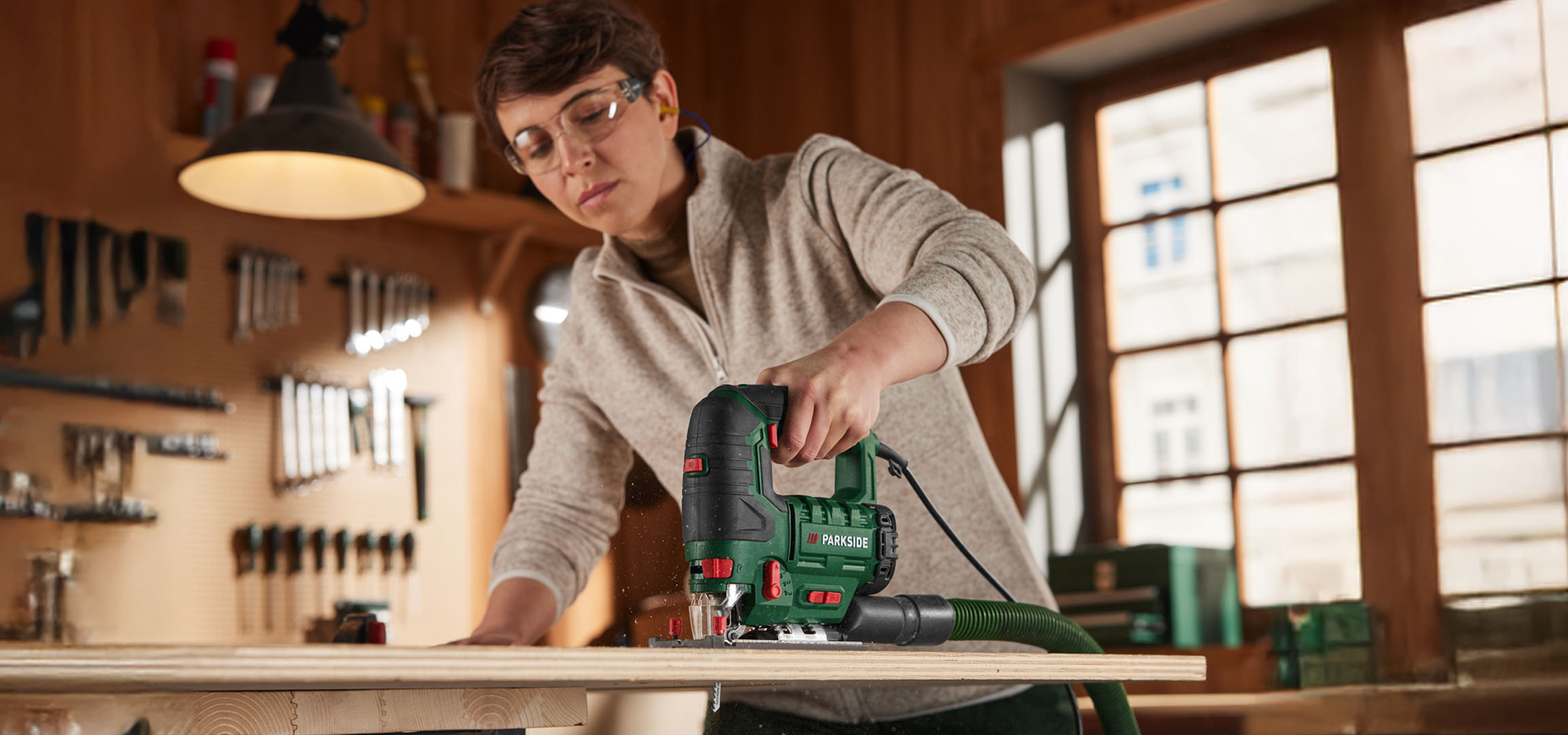 Frau verwendet eine Parkside Stichsäge zum Holz sägen.