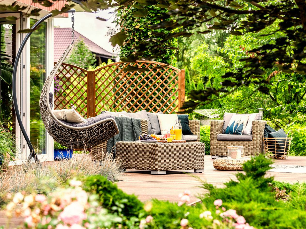 Hängesessel, Korbsofa und Couchtisch im Garten.