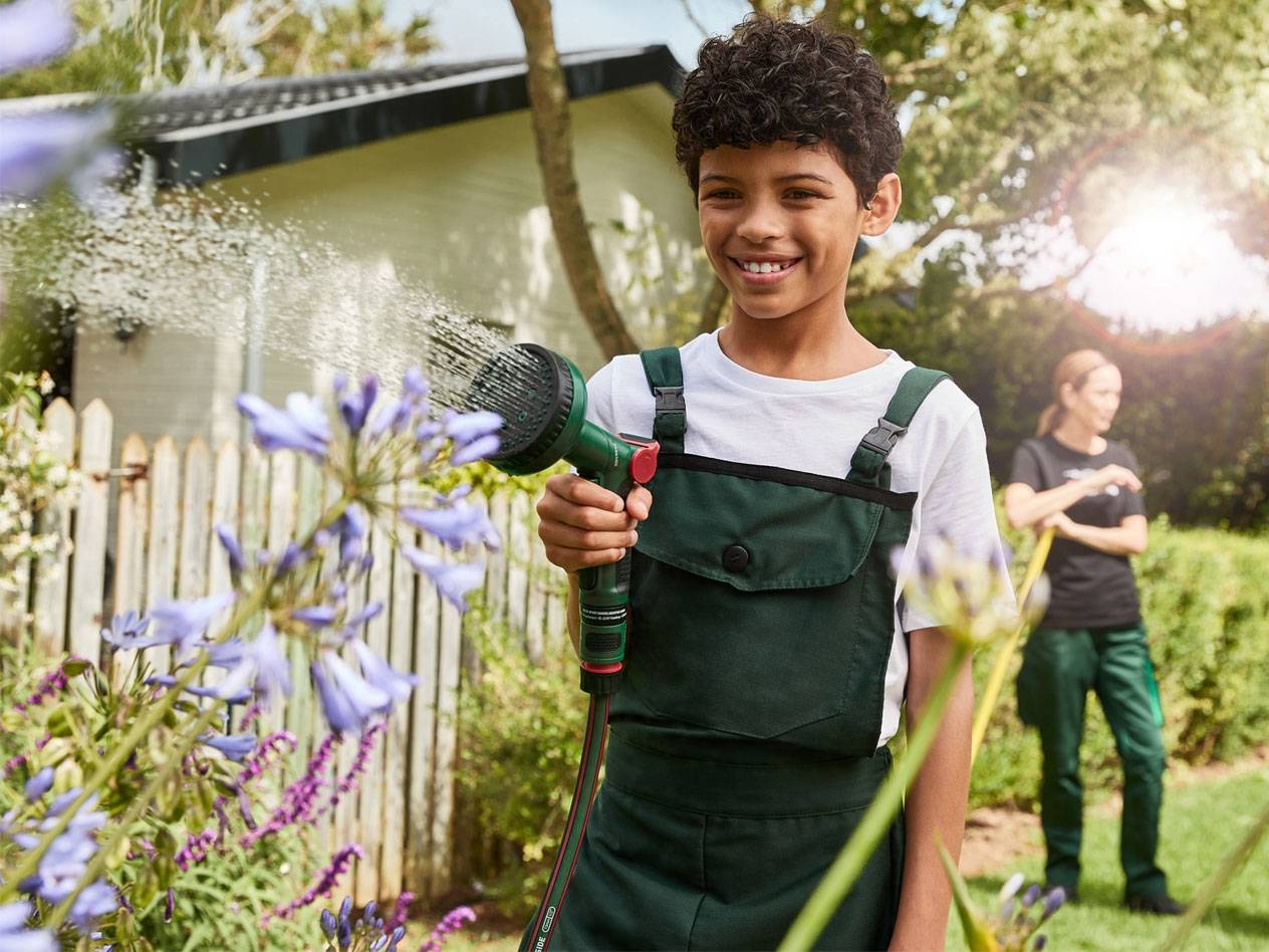 Junge gießt Blumen mit Gardena Schlauch.