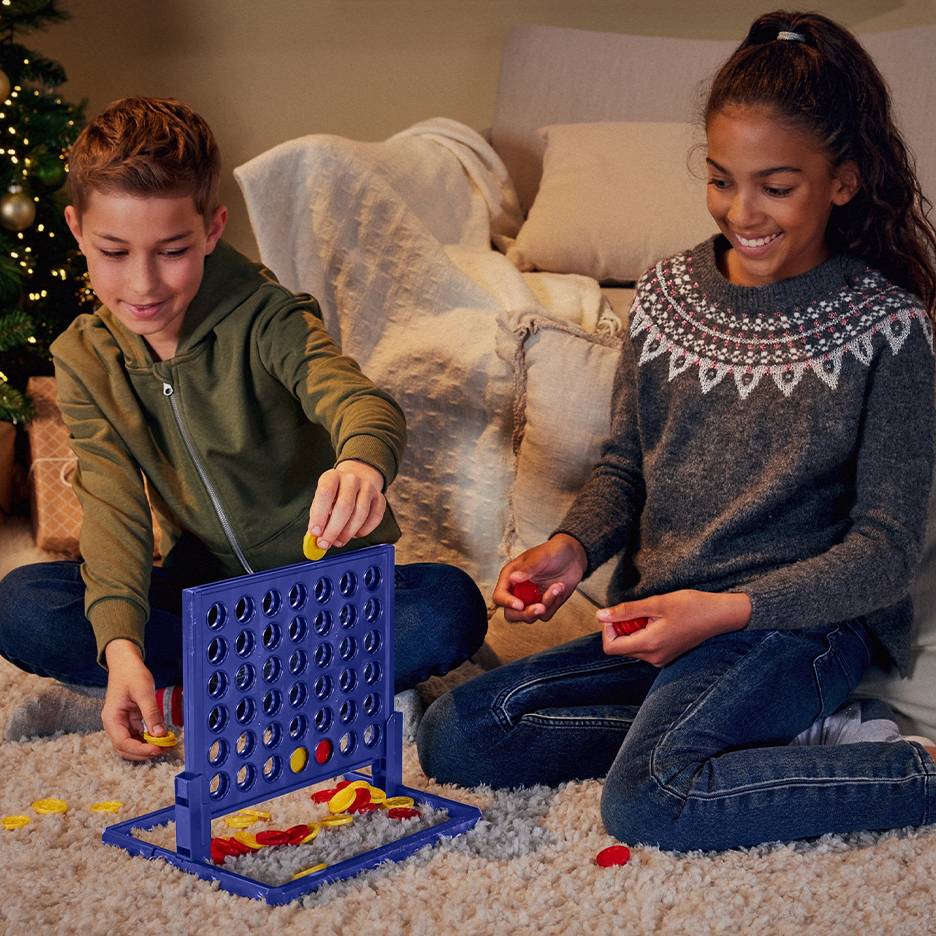 Zwei Kinder spielen Vier gewinnt in einem Wohnzimmer.