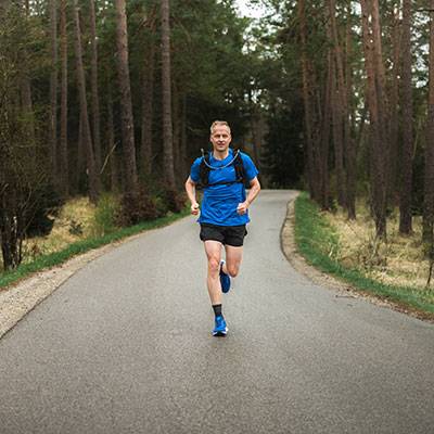Mann joggt im Wald in Sportkleidung.