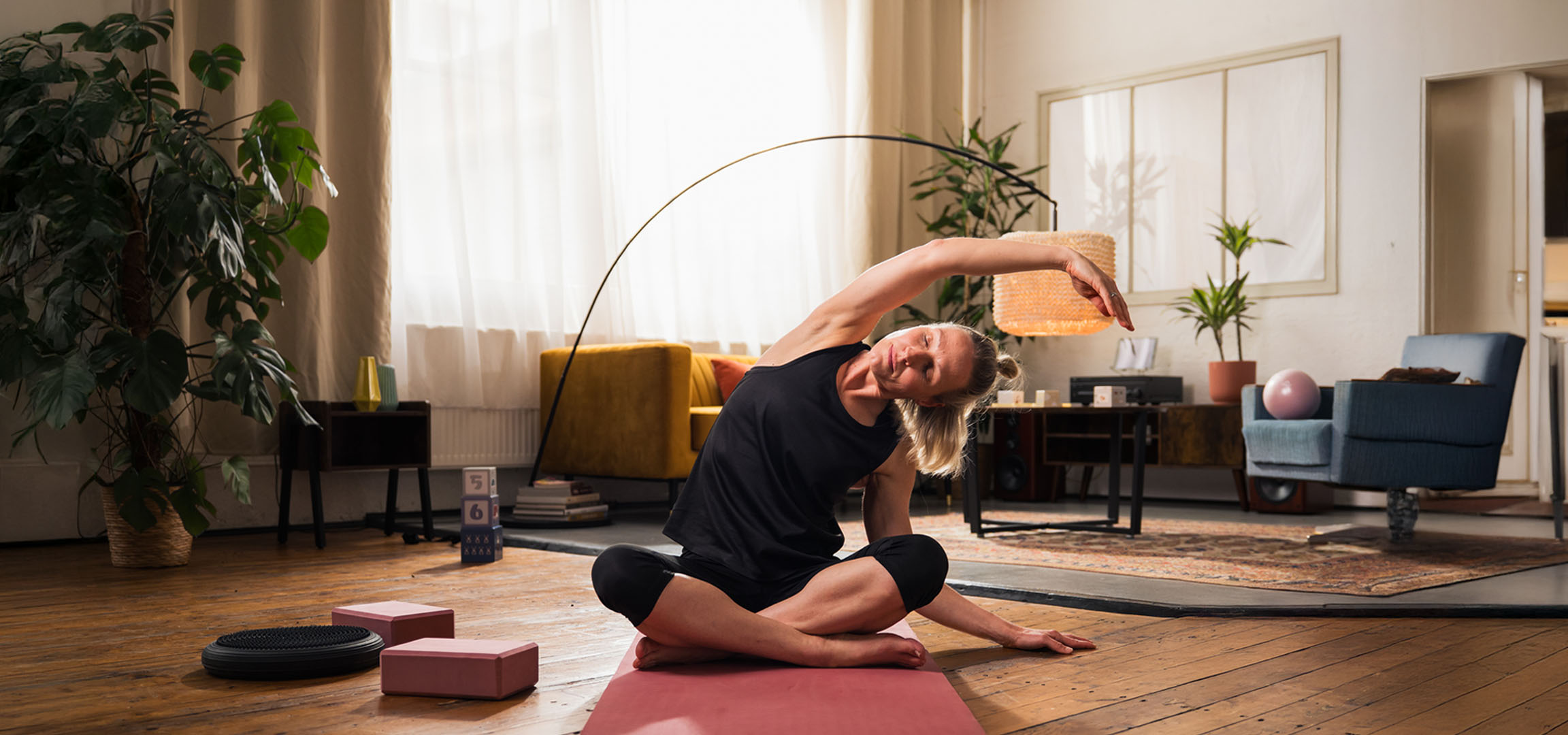 Frau macht Yoga zu Hause mit Matte und Blöcken.