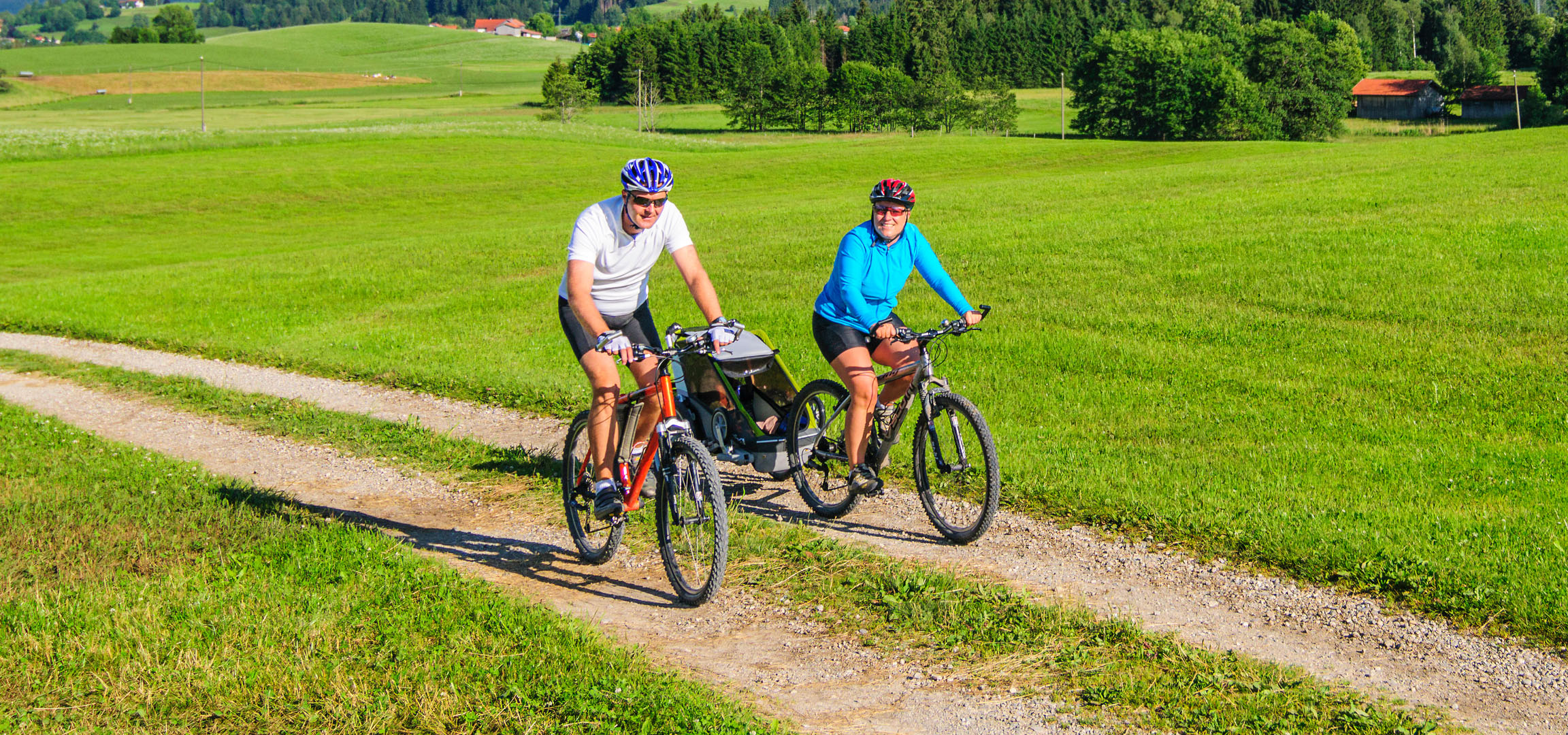 Paar fährt Fahrrad in grüner Landschaft.