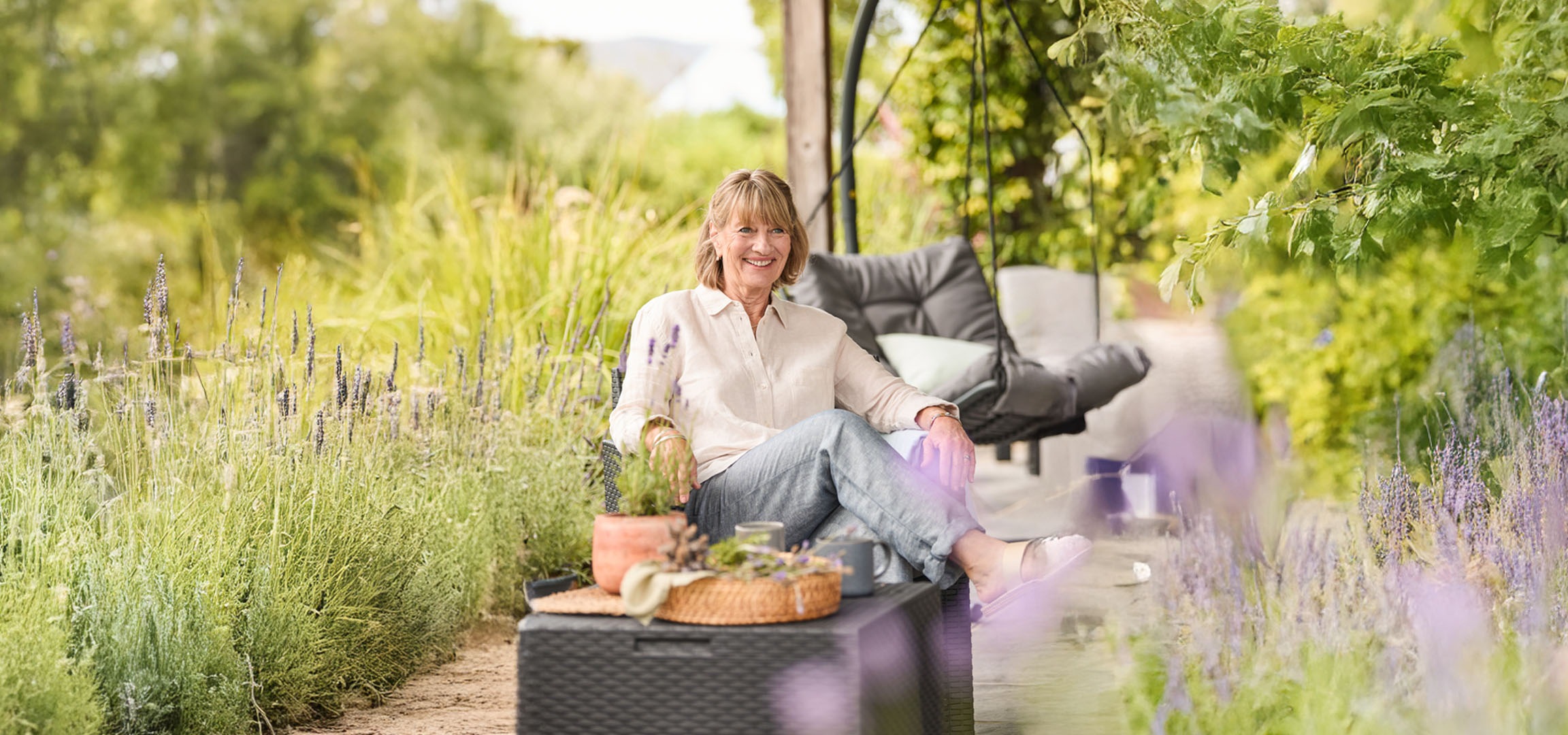 Frau entspannt sich im Garten mit Gartenmöbeln.