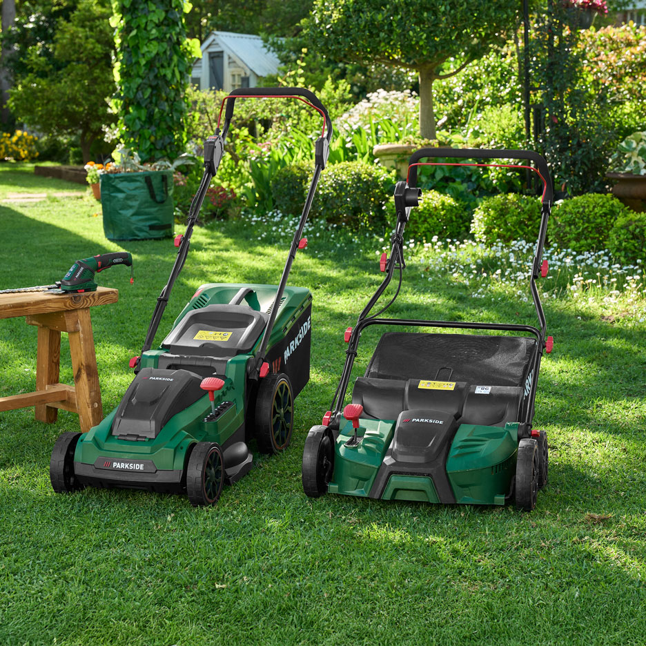 Zwei grüne Rasenmäher und eine Heckenschere auf einer Holzbank in einem sonnigen Garten.