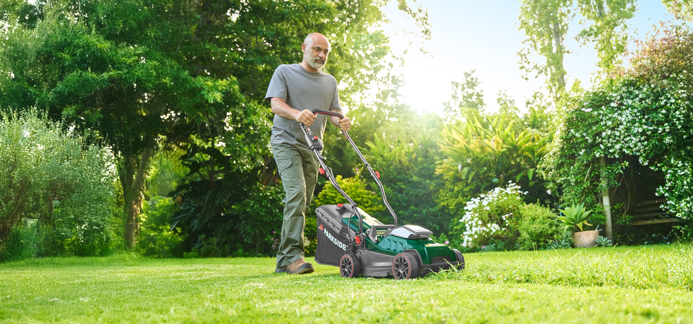 Mann mäht Rasen mit einem Parkside Rasenmäher.