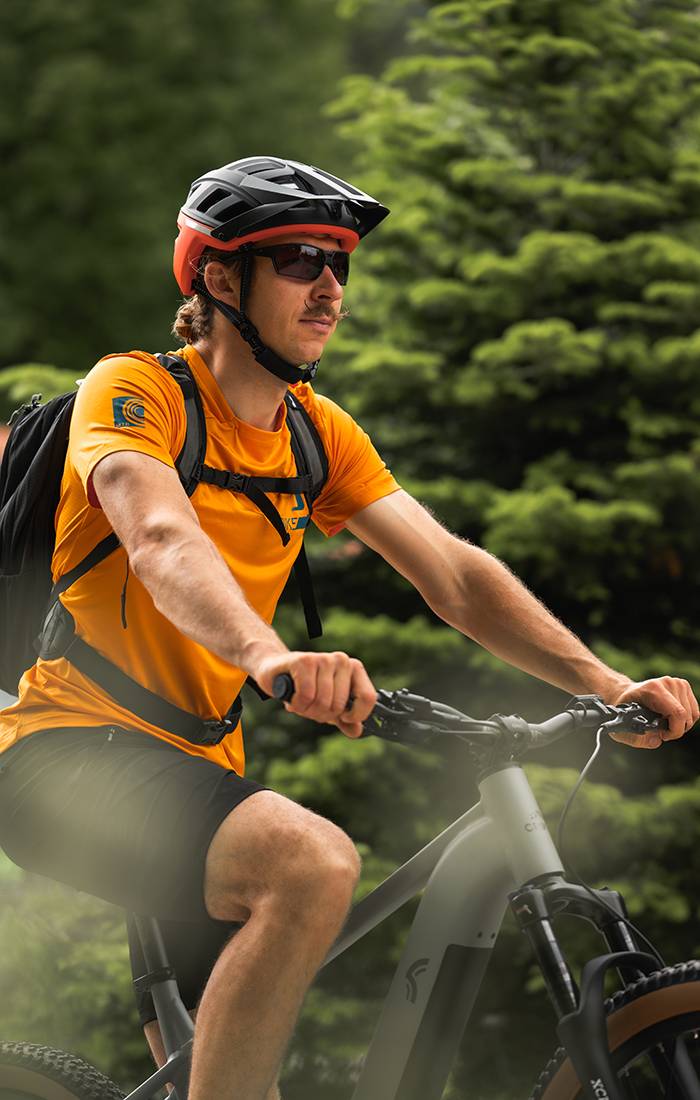 Mann fährt Mountainbike, trägt Helm und Sportkleidung.