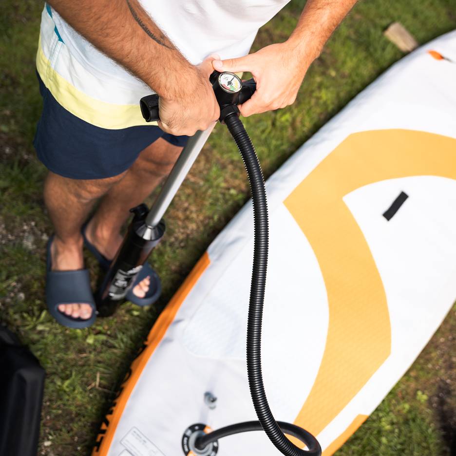 Mann pumpt ein aufblasbares Paddleboard mit einer Handpumpe auf.