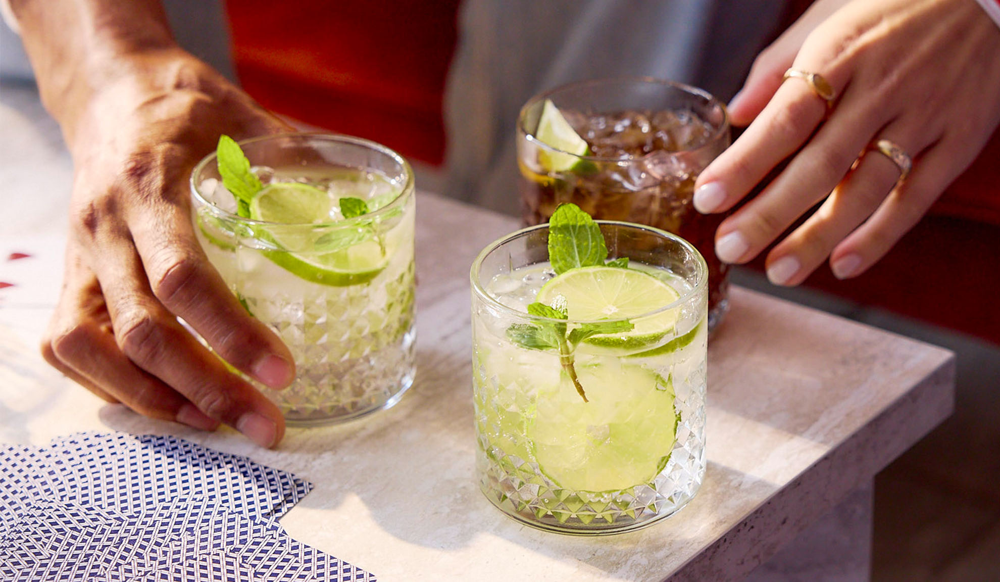 Mojitos und Cola in Gläsern.